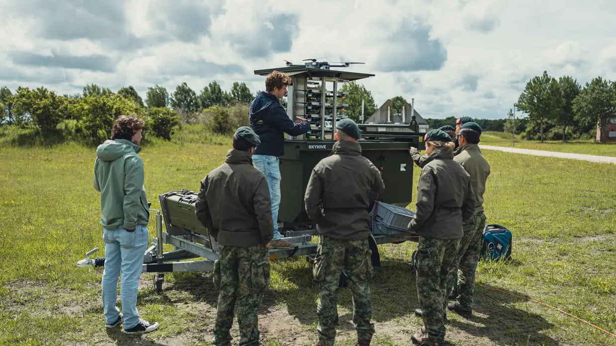 Vier militairen en twee andere mannen staan om het SkyHive-systeem.