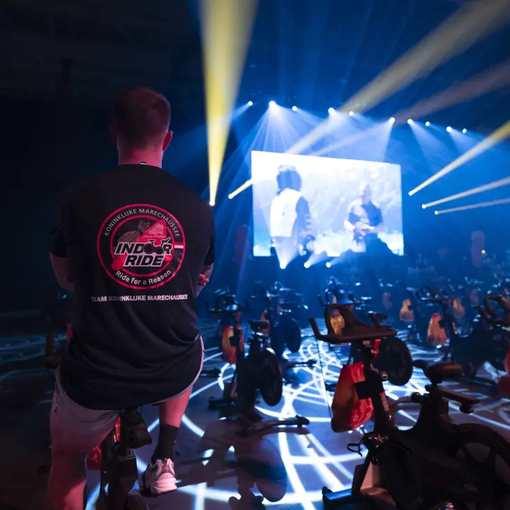 Deelnemer van team Marechaussee aan de Alpe d’HuZes Indoorride 2026, op de rug gezien, met shirt van de Marechaussee aan. 