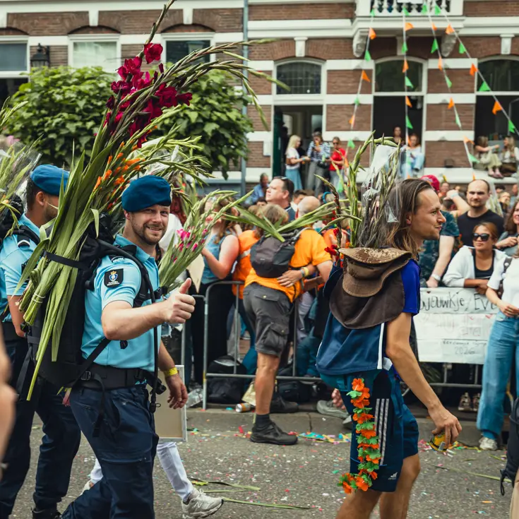 Twee marechaussees met een bos gladiolen op de rug, bij de finish van de Nijmeegse 4Daagse.
