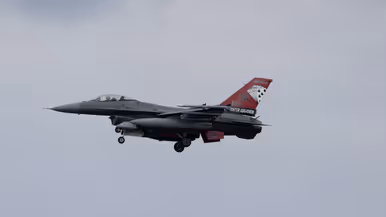 Een F-16 in de landing onder een blauwe lucht. 