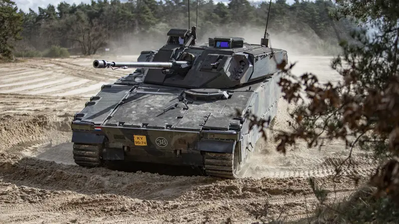 Een CV90 rijdt door het stuifzand. 