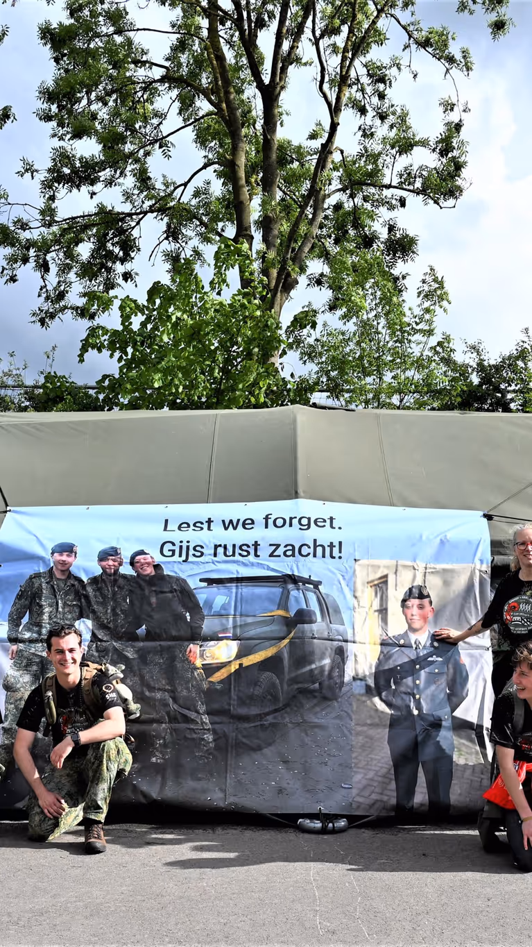 De lopers voor een groene tent waar een banner aan hangt.  