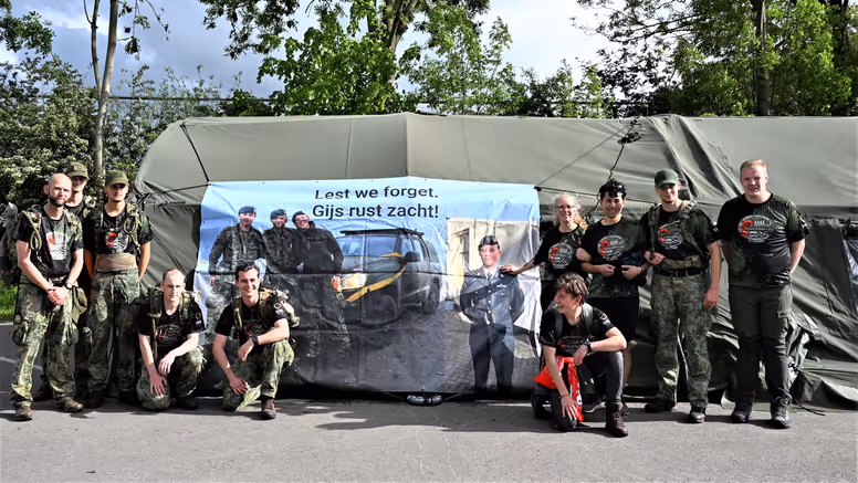 De lopers voor een groene tent waar een banner aan hangt.  