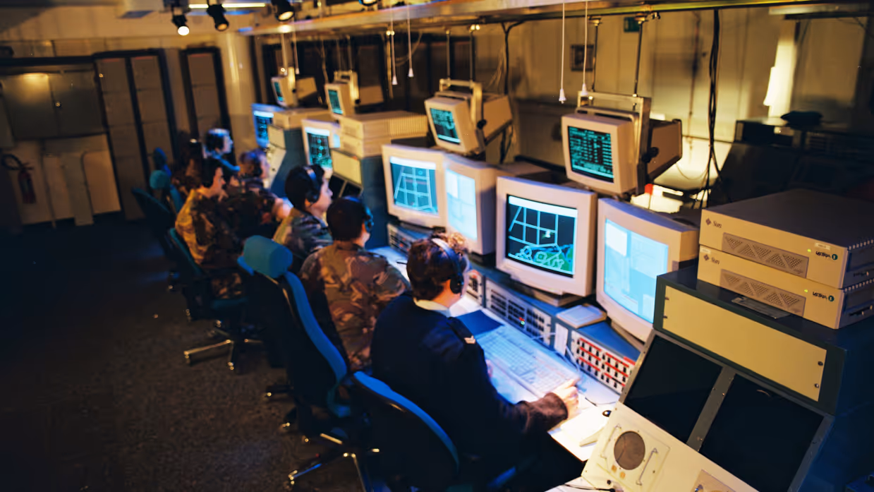 Een militair van de marine naast luchtmachters achter computerschermen. 