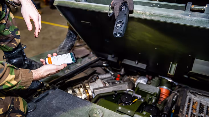Militair houdt digitale handleiding bij voertuig in onderhoud.
