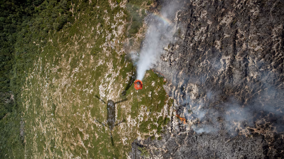 Een bambi bucket hangt onder een Chinook.