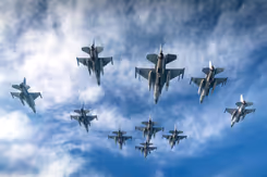 Vliegende F-16's met blauwe lucht en wolken op de achtergrond.