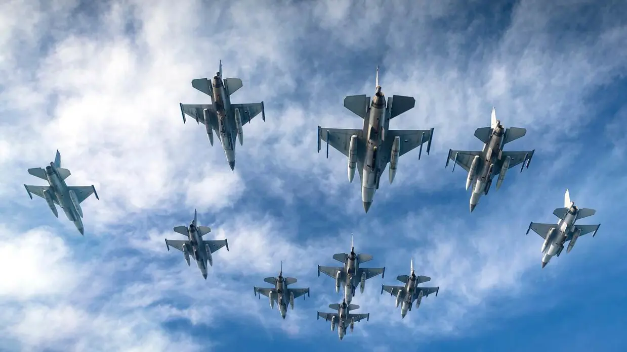 10 Nederlandse F-16's van onderaf gezien terwijl ze in formatie vliegen.