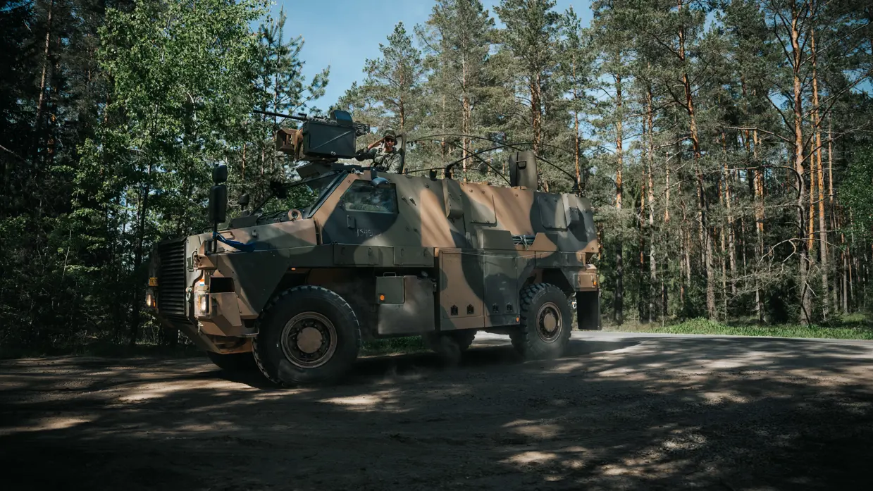 Een defensievoertuig van het type Bushmaster in het bos, die afslaat richting de camera