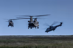 Drie helikopters vliegen laag boven de grond.