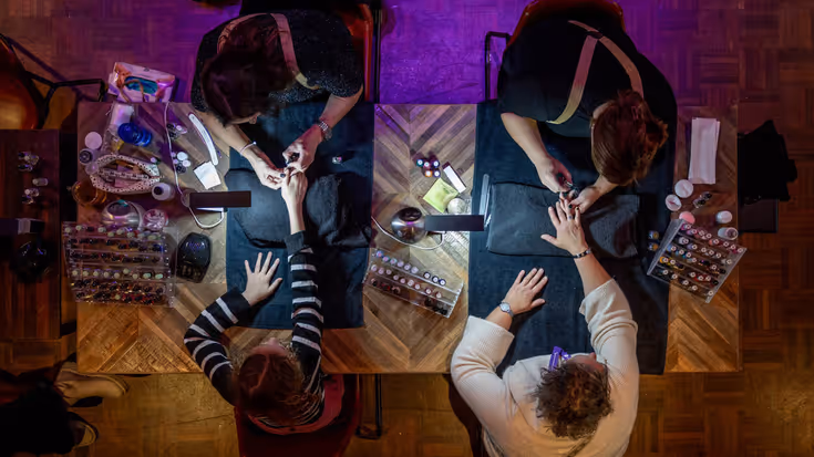 Twee dames krijgen een manicure, van bovenaf gezien en belicht door een klein lampje.