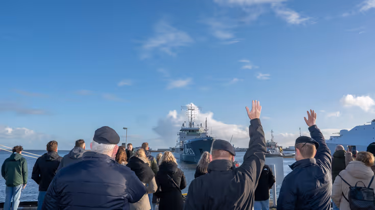 Mensen zwaaien een marineschip uit.