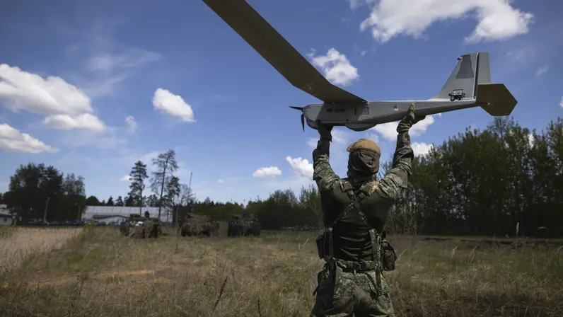 Een militair lanceert een drone boven zijn hoofd.