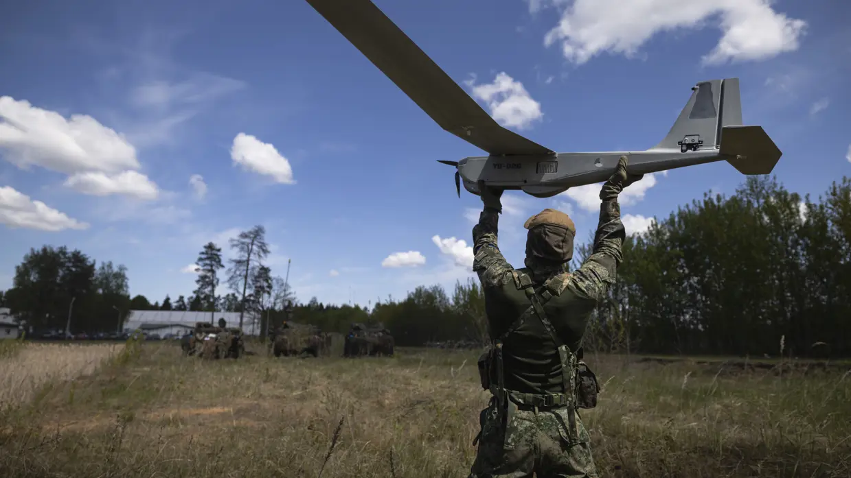 Een militair lanceert een drone boven zijn hoofd.