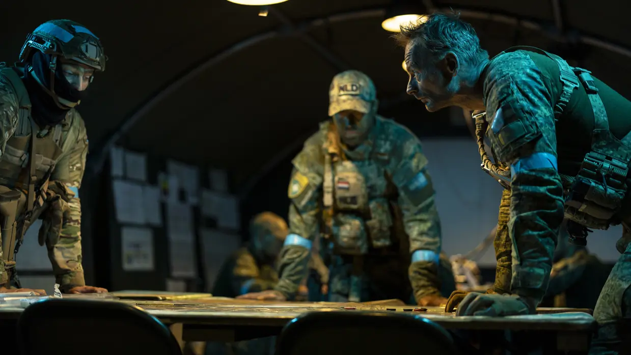 Een groep van drie militairen buigt over een kaart op tafel en overlegt.