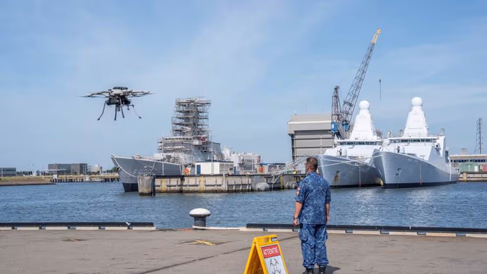 Militair staat op kade en kijkt naar drone die opstijgt.