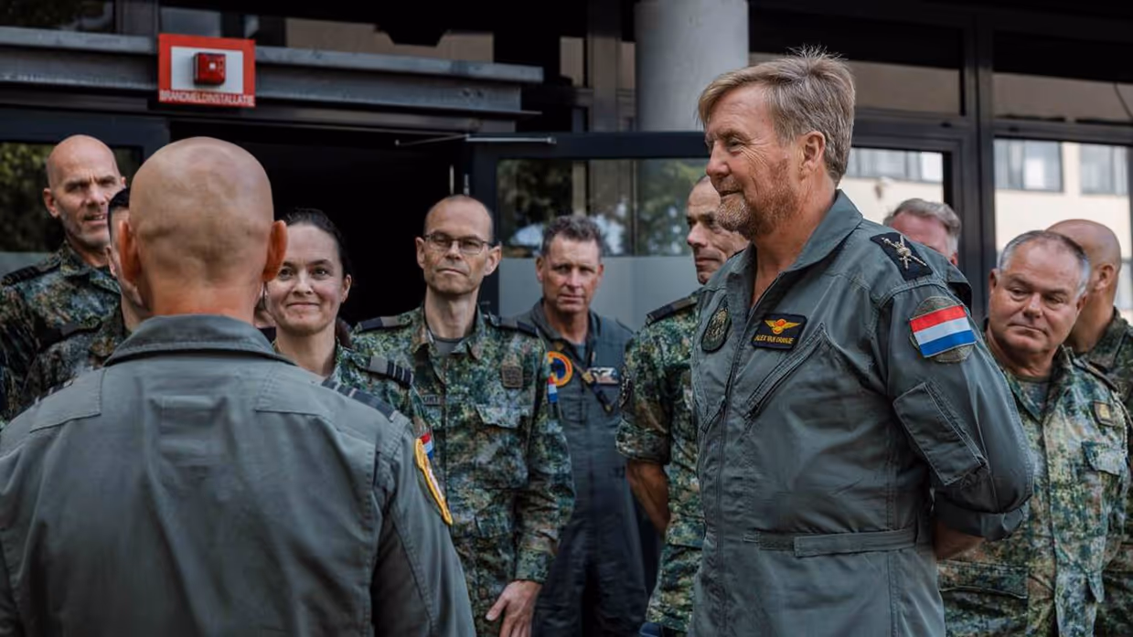 Koning Willem-Alexander in luchtmacht overall in gesprek met militairen.