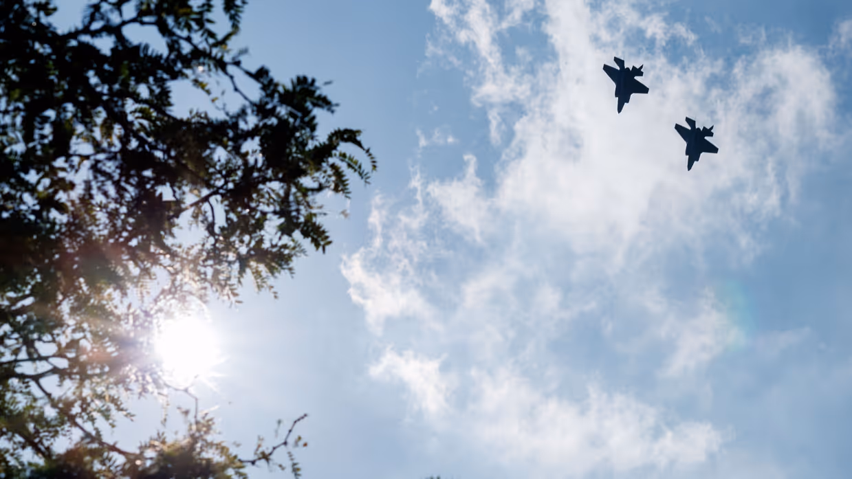 twee f-35’s draaien naar rechts weg, links staan bomen. 