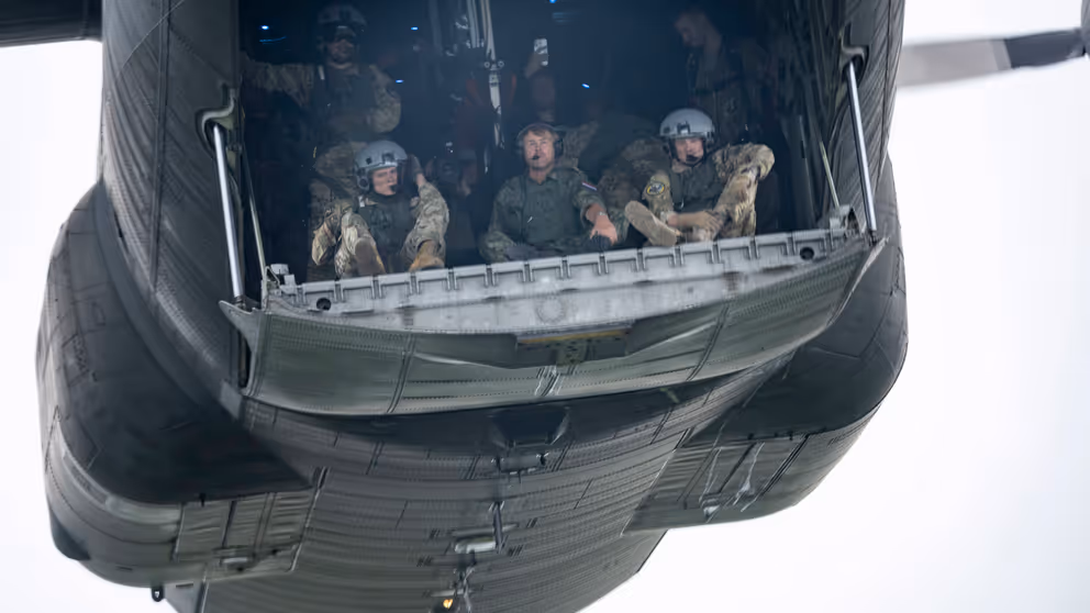 Parachutisten zitten klaar om uit het vliegtuig te springen. In het midden de koning.