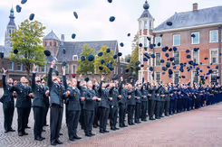 Officieren gooien hun pet in de lucht.