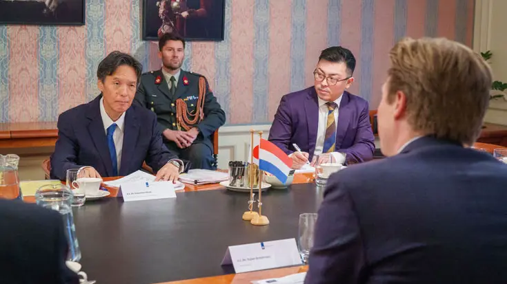 De ambassadeur en de minister overleggen met elkaar aan tafel.