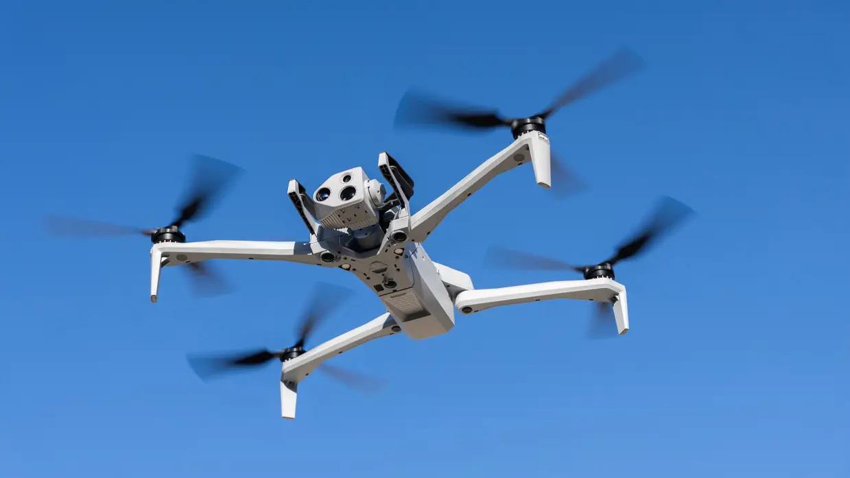 De drone van FO verkeer & visualisatie hangt in de lucht met de camera naar voren gericht en een blauwe lucht op de achtergrond.