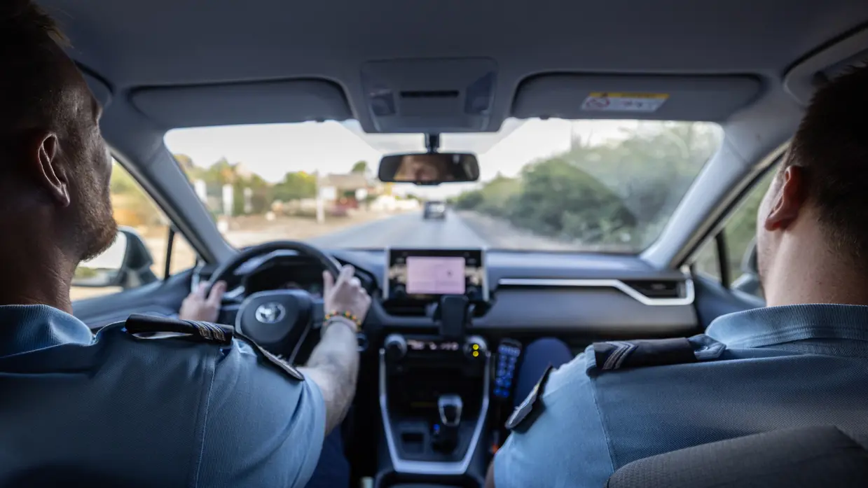 Twee marechaussees in een voertuig op Aruba, op de rug gezien.