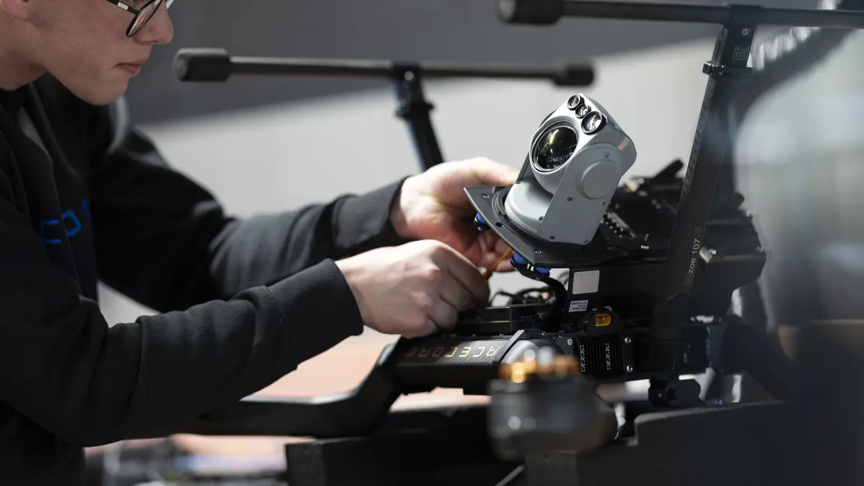 Een medewerker van Acecore schroeft een camera onder een drone.