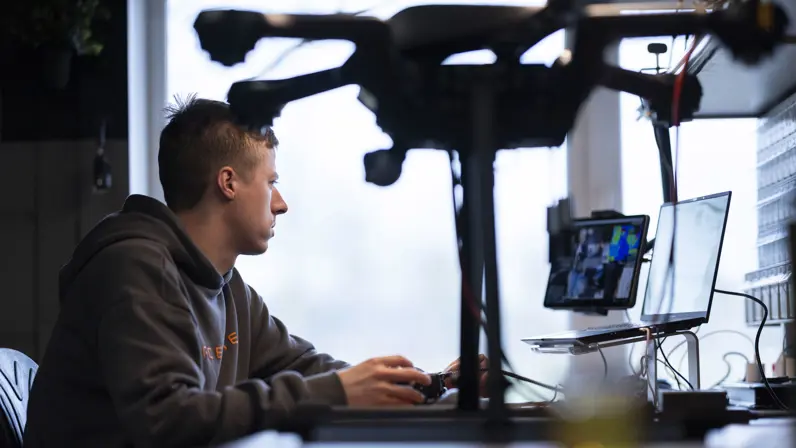 Een medewerker van Acecore zit aan zijn bureau, op de voorgrond een drone.