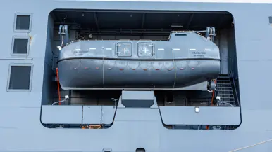 Een grijze kraan op het dek van het schip, een donkergrijze reddingsboot en het predicaat met daarop ‘Den Helder’.
