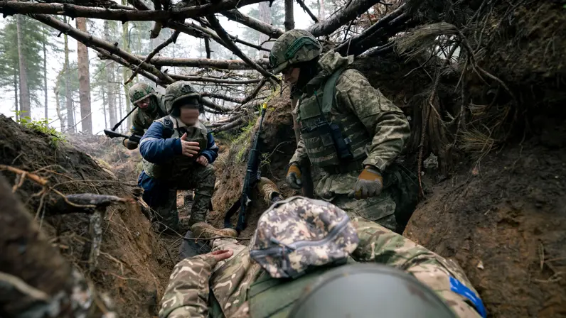 Drie Oekraïense militairen en een tolk in een loopgraaf bij een LOTUS-slachtoffer.