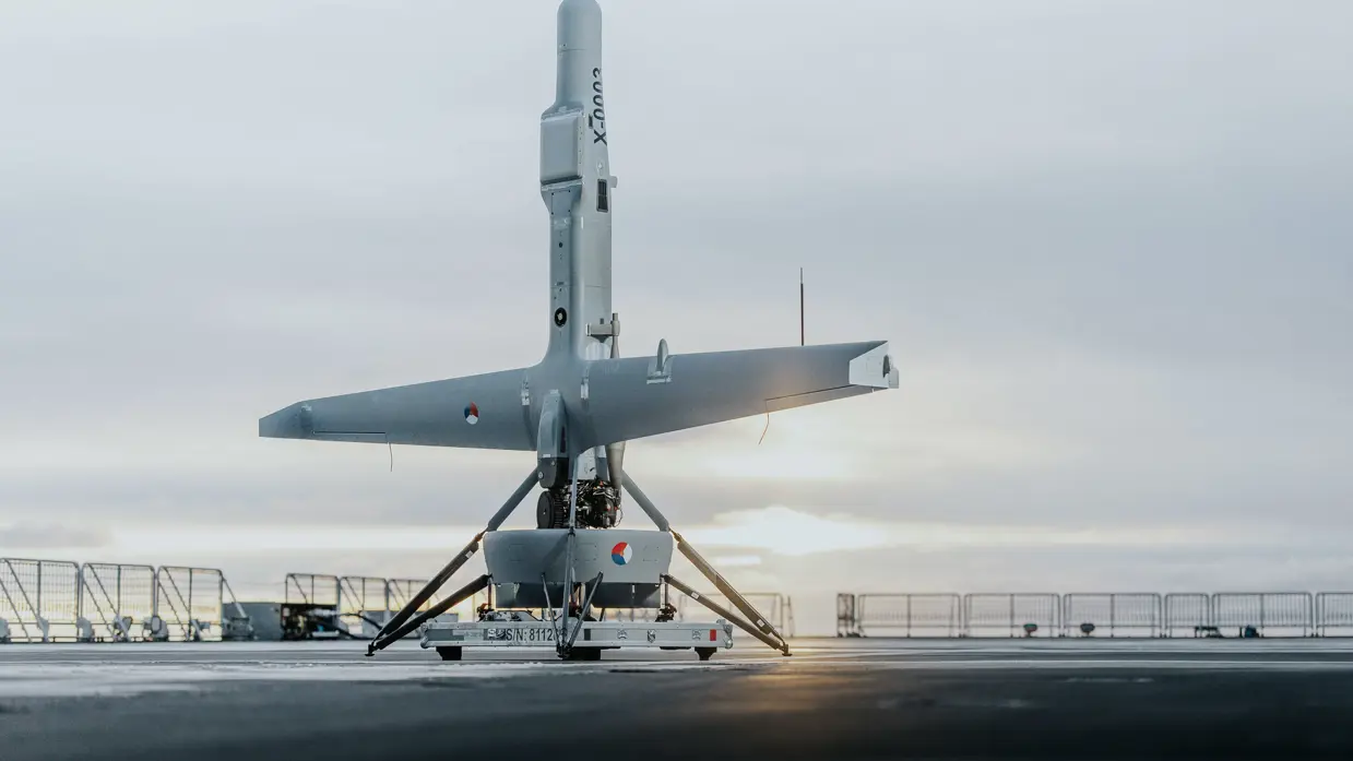 Een V-BAT drone staat naar boven gericht op het dek van een schip.