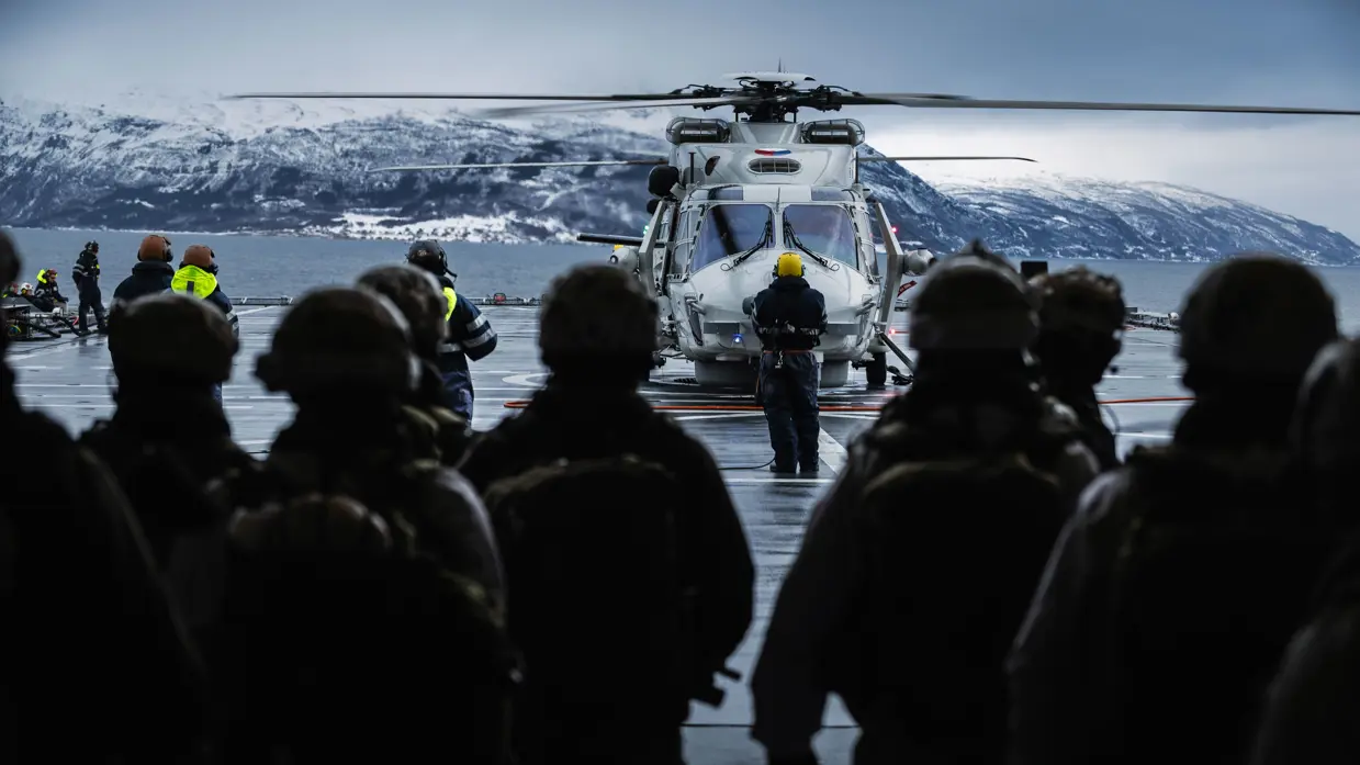 Een NH90 landt op het helidek van Zr.Ms. Johan de Witt, terwijl opvarenden toekijken. 