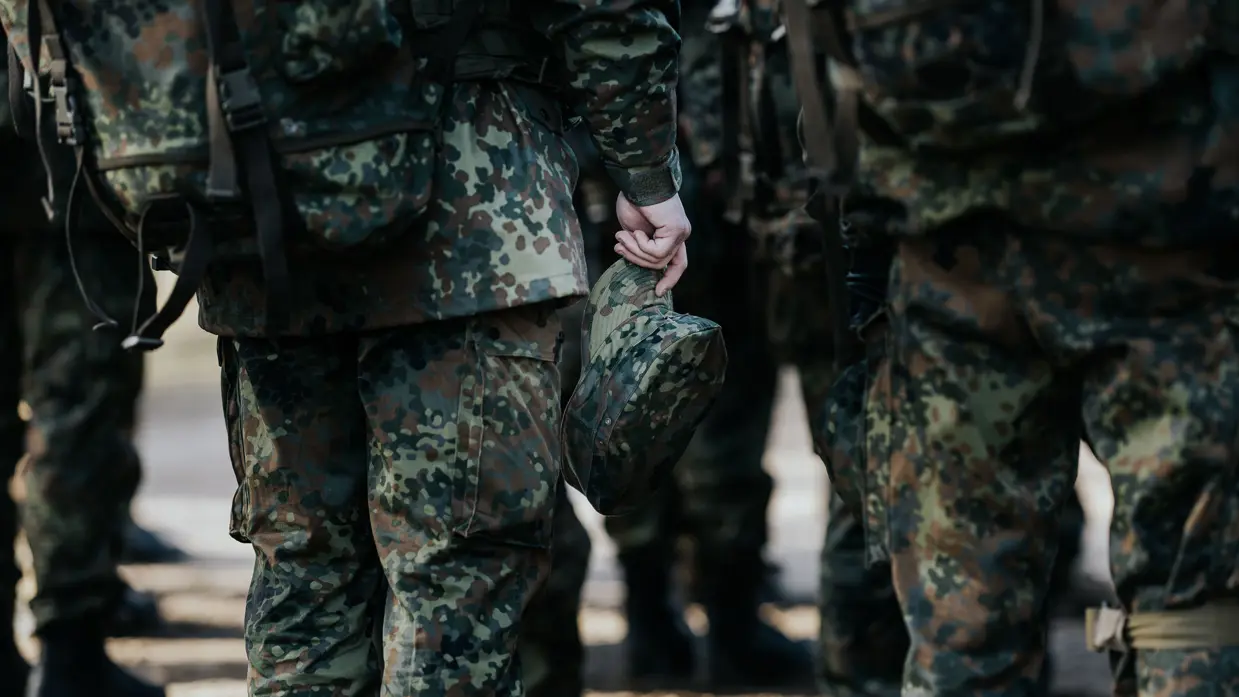 Een militair houdt zijn pet in de hand. 
