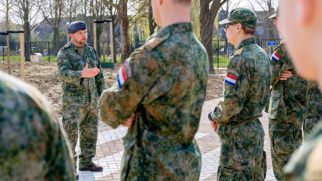 Buiten staat een rijtje jongeren in gevechtspak. Ervoor staat sergeant-majoor Tim Nelissen die hen toespreekt.