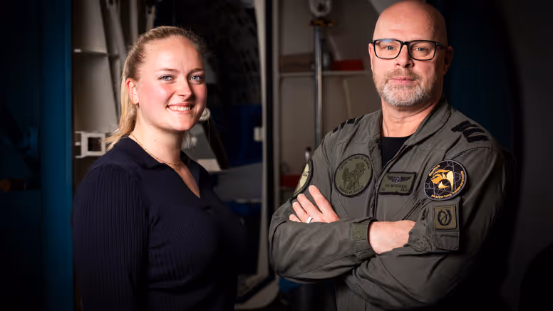 Vrouw in burgerkleding en man in militair uniform staan naast elkaar. 