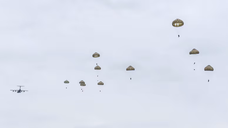 Parachutisten dalen met geopende parachutes neer boven de Belgische heide tijdens oefening Versatile Guard 