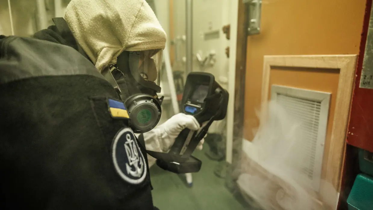 Een brandbestrijder controleert rook die uit rooster van een deur komt