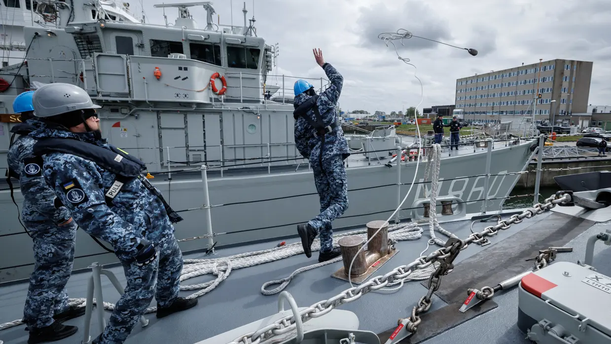 Een militair gooit een tros naar de kade om aan te leggen