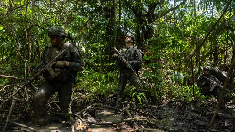 2 militairen lopen op patrouille door de jungle.