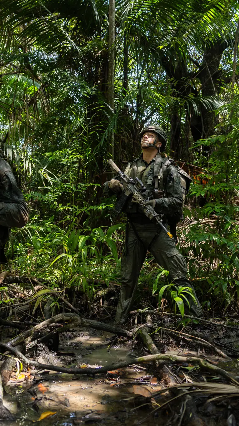 2 militairen lopen op patrouille door de jungle.