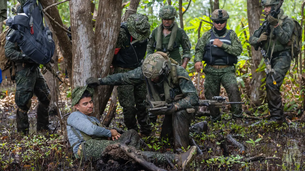 Op de 4 foto’s een Colombiaanse instructeur in een boom, Colombiaanse instructeurs die zogenaamd drugs verstoppen, een Colombiaanse instructeur die een drugslab optuigt en mariniers met een zogenaamd neergeschoten kartelbaas.