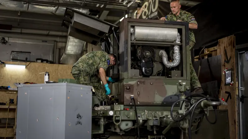 Twee militairen sleutelen aan een aggregaat.