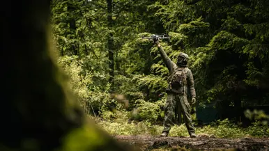Een militair laat een drone opstijgen in het bos.