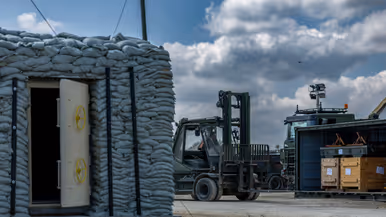 Op de linkerfoto rijdt een vorkheftruck naar een container. Op de rechterfoto zijn militairen bezig met een radarsysteem.