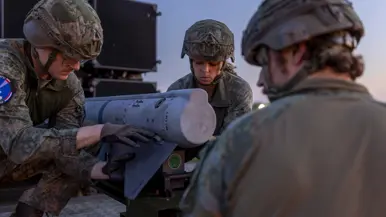 Op de linkerfoto een NASAMS-lanceerinrichting in het avondrood. Op de rechterfoto monteren militairen stabilisatievinnen op een luchtdoelraket.