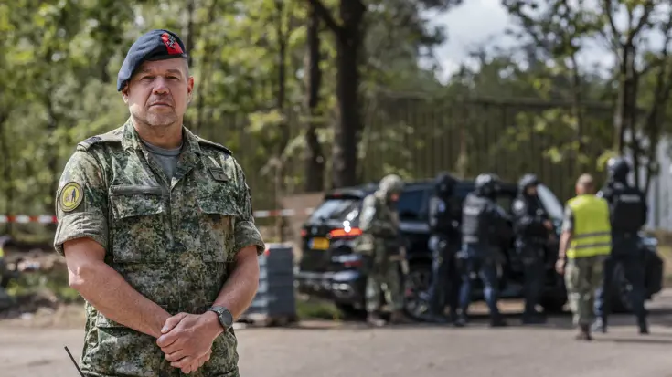 Eerste luitenant der mariniers Hans in uniform op de voorgrond met de BBTIN-eenheid op de achtergrond in actie.