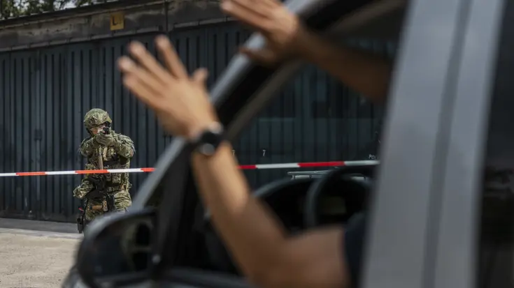 Militair heeft zijn wapen in de aanslag tegenover een auto waar een verdachte persoon zijn handen omhoog steekt.