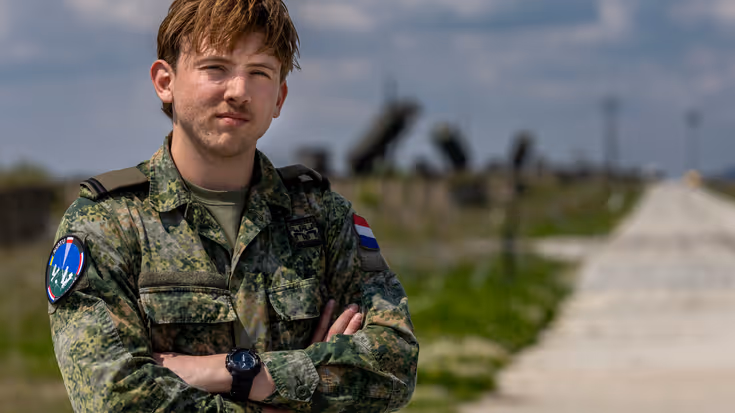 Ronan staat met de armen over elkaar. Op de achtergrond staan Patriot-lanceerinstallaties.