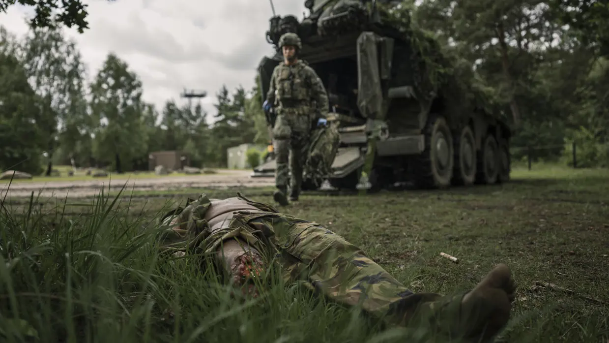 Een militairen loopt naar een gewonde collega.